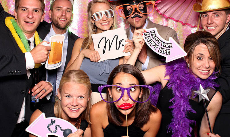Guests crowded into the photo booth with props, mid-laugh